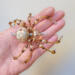Handmade wire spider ornament in gold, cream, and honey-toned beads on a neutral background